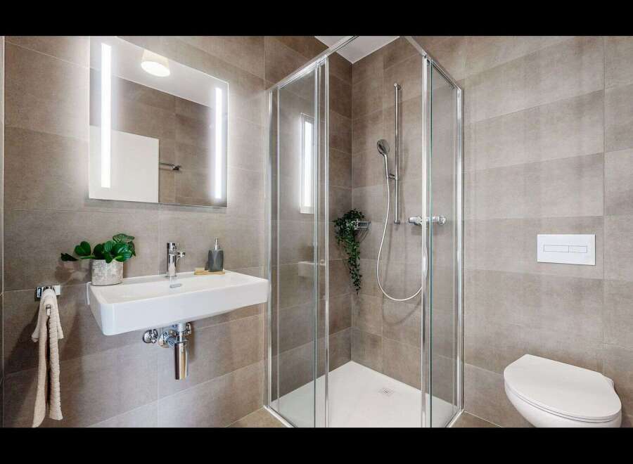 Experience modern comfort in this beautifully appointed bathroom, featuring a sleek wall-mounted sink and a spacious glass-enclosed shower.