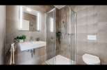 Experience modern comfort in this beautifully appointed bathroom, featuring a sleek wall-mounted sink and a spacious glass-enclosed shower.
