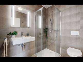 Experience modern comfort in this beautifully appointed bathroom, featuring a sleek wall-mounted sink and a spacious glass-enclosed shower.
