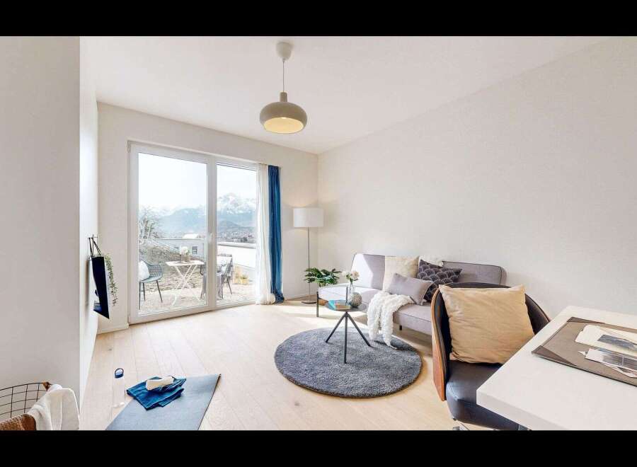 Experience modern living in this bright and airy apartment, featuring a spacious living area with large windows offering stunning mountain views.