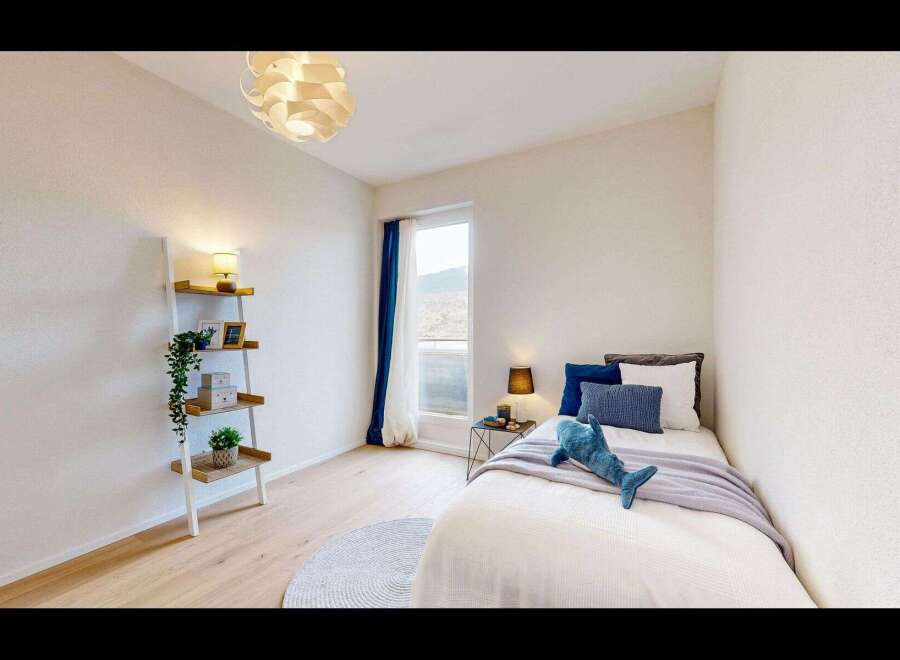 Discover this charming bedroom featuring a cozy single bed adorned with plush pillows and a playful shark plushie.