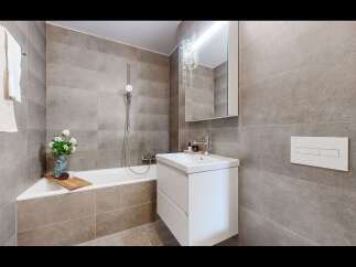 This modern bathroom features a sleek white vanity with ample storage, complemented by a spacious bathtub and a rainfall showerhead.