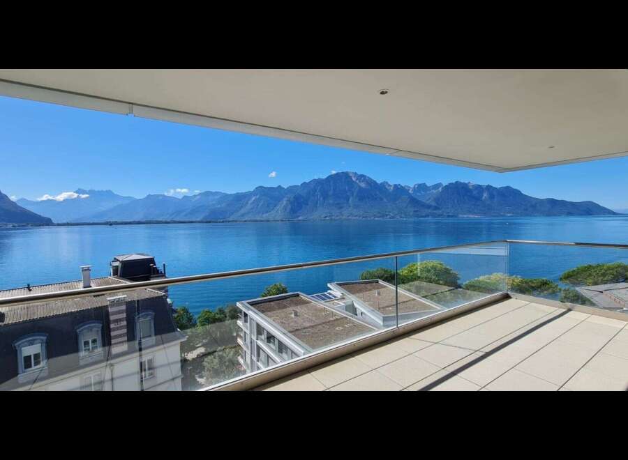 Experience breathtaking panoramic views of a serene lake and majestic mountains from this stunning balcony.