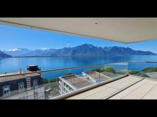 Experience breathtaking panoramic views of a serene lake and majestic mountains from this stunning balcony.
