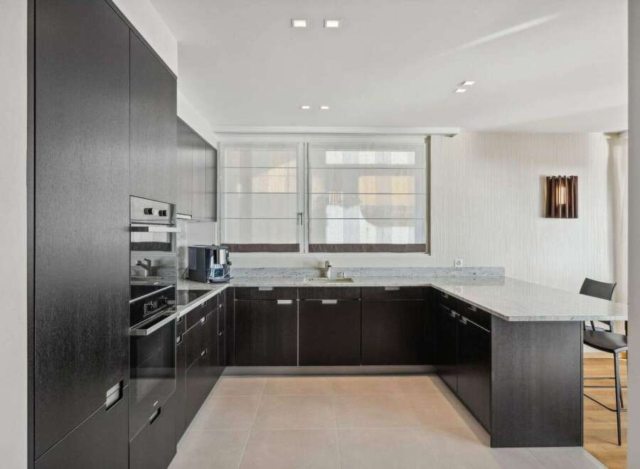 Experience modern luxury in this sleek kitchen featuring dark wood cabinetry and a stunning granite countertop.