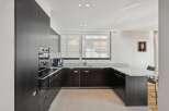 Experience modern luxury in this sleek kitchen featuring dark wood cabinetry and a stunning granite countertop.