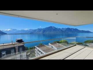 Experience breathtaking panoramic views of a serene lake and majestic mountains from this stunning balcony.