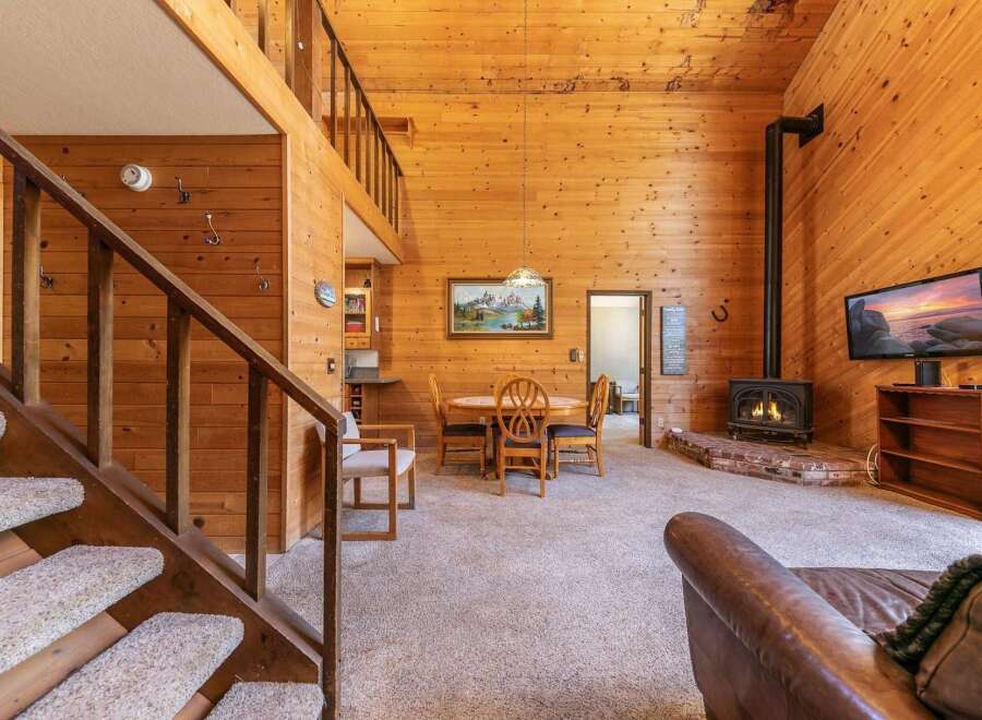Experience rustic charm in this cozy cabin featuring a soaring wood-paneled ceiling and a warm, inviting fireplace.