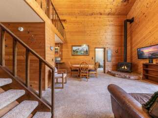 Experience rustic charm in this cozy cabin featuring a soaring wood-paneled ceiling and a warm, inviting fireplace.