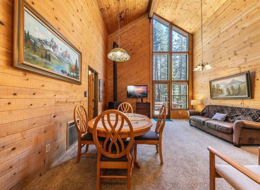 Experience rustic charm in this cozy cabin living area, featuring a dining table with four chairs and a comfortable leather sofa.