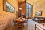 Experience rustic charm in this cozy cabin living area, featuring a dining table with four chairs and a comfortable leather sofa.