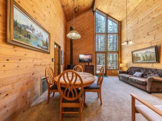 Experience rustic charm in this cozy cabin living area, featuring a dining table with four chairs and a comfortable leather sofa.