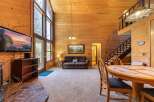 Experience rustic charm in this spacious living area featuring a soaring wood-paneled ceiling and a wall of windows that flood the space with natural light.