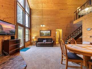Experience rustic charm in this spacious living area featuring a soaring wood-paneled ceiling and a wall of windows that flood the space with natural light.