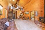 Experience rustic charm in this cozy living space featuring a warm, wood-paneled interior and a prominent brick fireplace with a wood-burning stove.