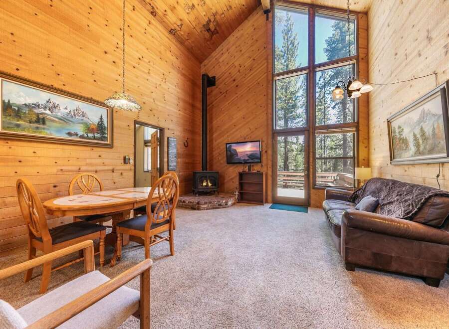 Experience cozy living in this charming cabin featuring a vaulted wood-paneled ceiling and a stunning floor-to-ceiling window that floods the space with natural light.