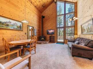 Experience cozy living in this charming cabin featuring a vaulted wood-paneled ceiling and a stunning floor-to-ceiling window that floods the space with natural light.