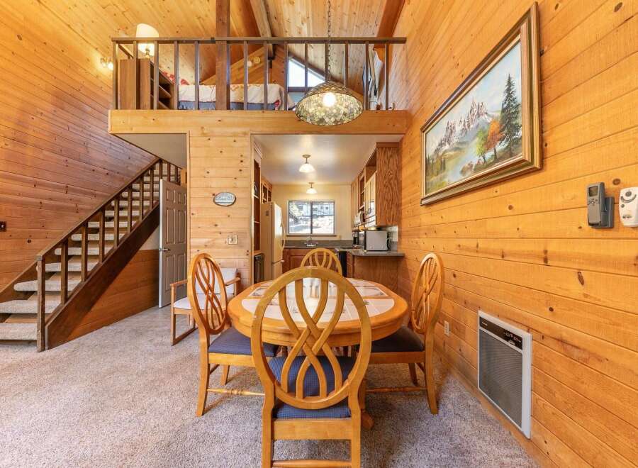 Experience cozy living in this charming cabin-style home featuring a warm, wood-paneled interior and a lofted bedroom area.
