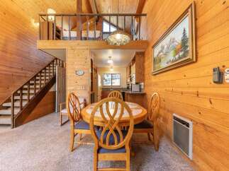 Experience cozy living in this charming cabin-style home featuring a warm, wood-paneled interior and a lofted bedroom area.