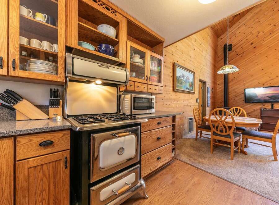 This charming kitchen boasts a vintage-style gas range and oven, complemented by ample wooden cabinetry and glass-front display shelves.