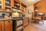 This charming kitchen boasts a vintage-style gas range and oven, complemented by ample wooden cabinetry and glass-front display shelves.
