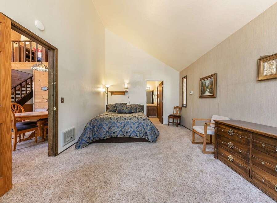Discover this charming bedroom featuring a comfortable queen-size bed adorned with a luxurious blue and gold damask comforter.