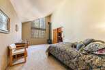 Experience rustic charm in this spacious bedroom featuring a vaulted ceiling and large windows that offer stunning forest views.