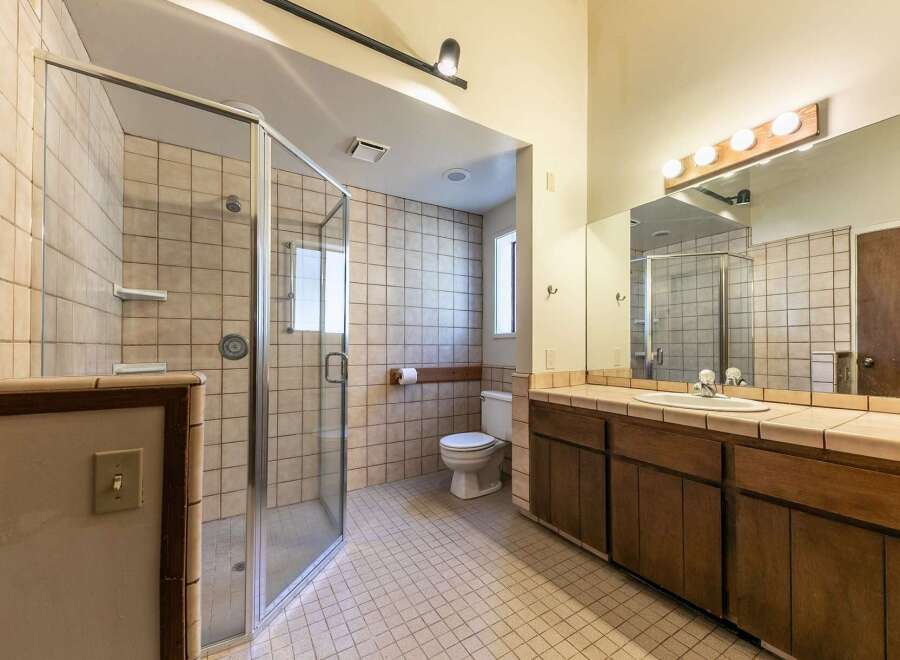This spacious bathroom features a large, glass-enclosed shower with tiled walls and a built-in shelf.