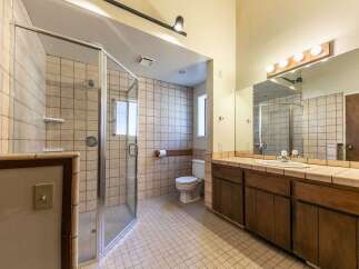 This spacious bathroom features a large, glass-enclosed shower with tiled walls and a built-in shelf.