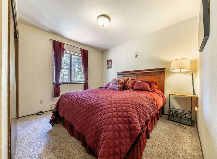 This cozy bedroom features a plush queen-sized bed adorned with rich burgundy bedding and decorative pillows.