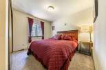 This cozy bedroom features a plush queen-sized bed adorned with rich burgundy bedding and decorative pillows.