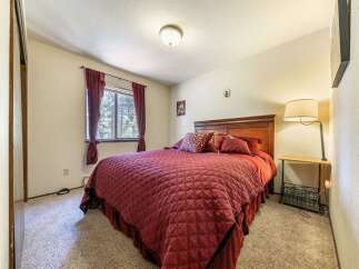 This cozy bedroom features a plush queen-sized bed adorned with rich burgundy bedding and decorative pillows.