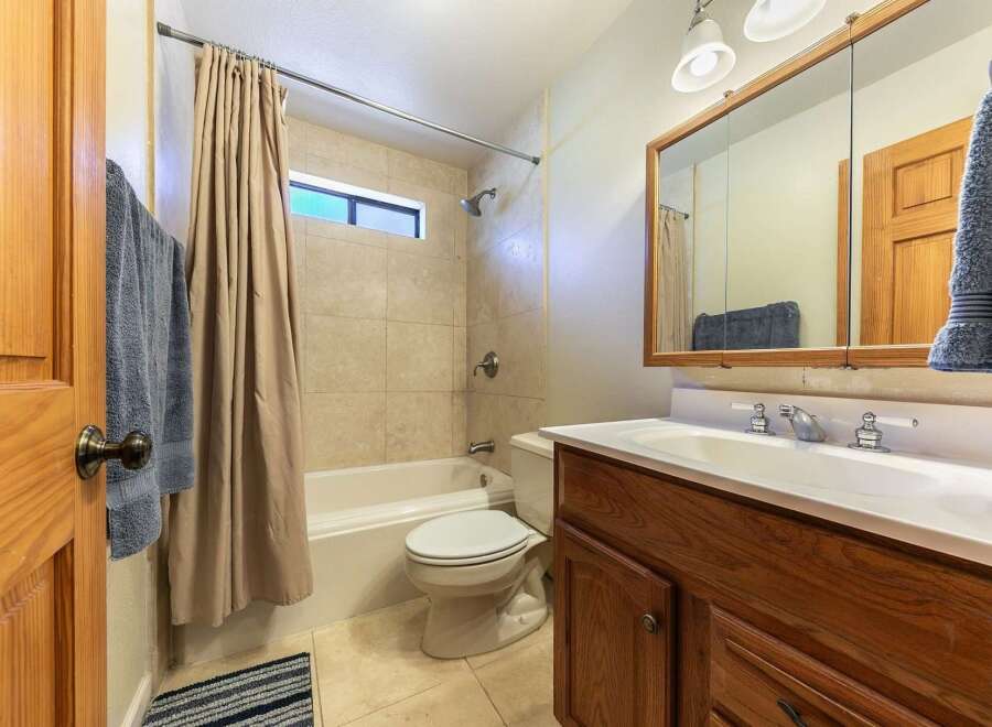 This bathroom features a classic design with a bathtub and shower combo, complemented by beige tiled walls.