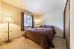 This cozy bedroom features a comfortable queen-size bed adorned with decorative pillows and a rich brown comforter.