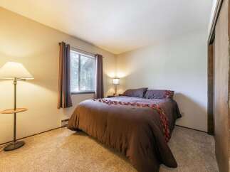 This cozy bedroom features a comfortable queen-size bed adorned with decorative pillows and a rich brown comforter.