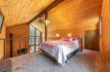 Experience rustic charm in this loft bedroom, featuring a cozy bed with vibrant patterned bedding and a stunning vaulted wood-paneled ceiling.