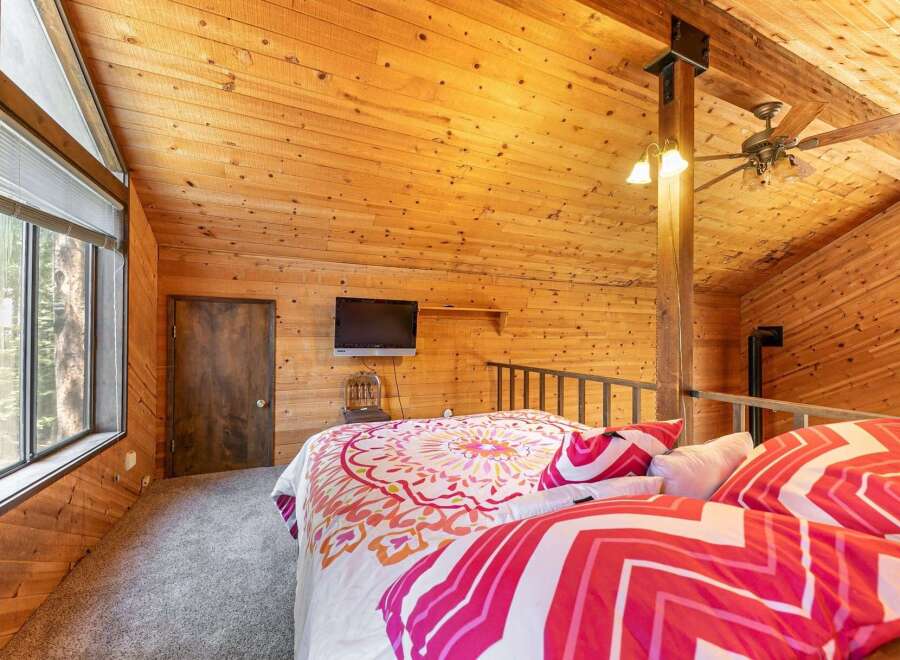 Experience rustic charm in this unique loft bedroom, featuring a cozy bed adorned with vibrant, patterned bedding.