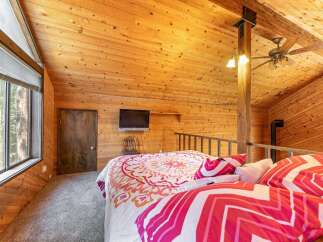 Experience rustic charm in this unique loft bedroom, featuring a cozy bed adorned with vibrant, patterned bedding.