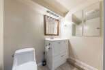 This bathroom features a modern white vanity with ample storage, complemented by a sleek faucet and a wooden-framed mirror.