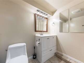 This bathroom features a modern white vanity with ample storage, complemented by a sleek faucet and a wooden-framed mirror.