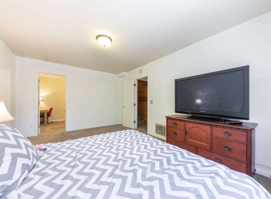 This cozy bedroom features a comfortable bed with a stylish gray and white chevron comforter, perfect for relaxation.