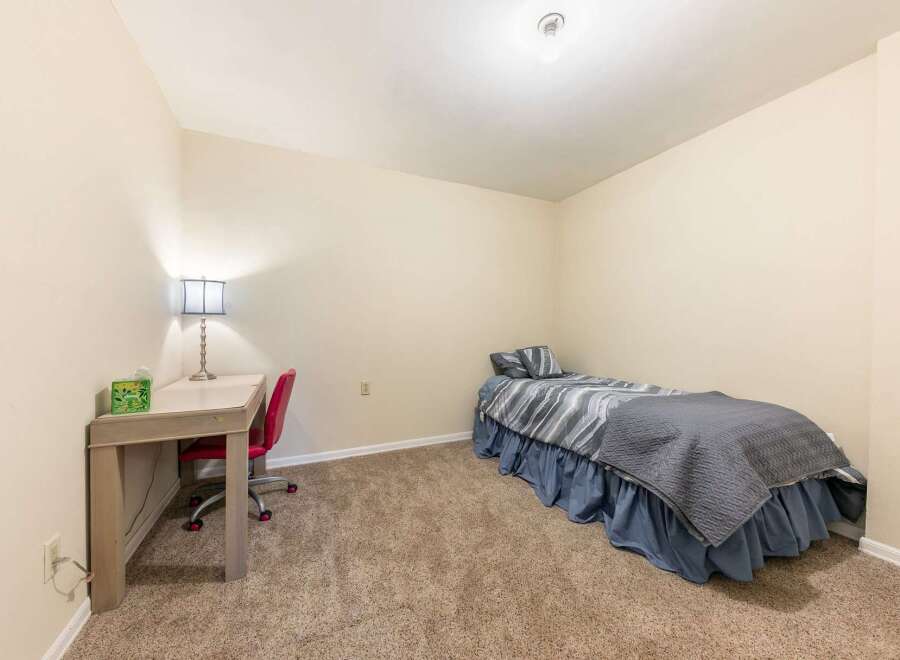 This cozy bedroom features a comfortable twin bed with stylish grey and blue bedding, perfect for a guest room or a child's space.