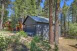 Discover this charming property nestled amongst tall pine trees, featuring a modern dark gray garage with a sleek metal roof.