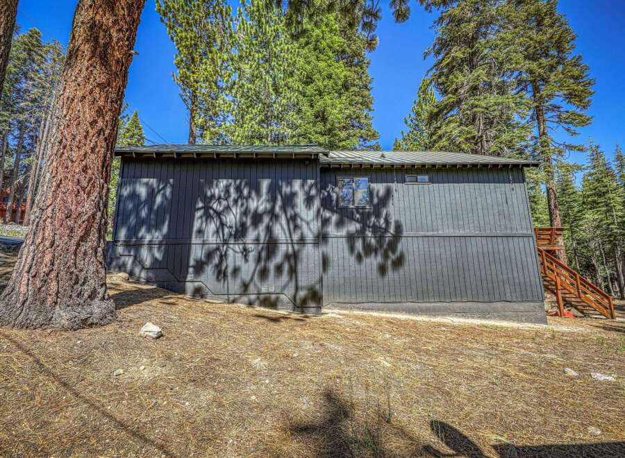 Nestled amongst tall pine trees, this dark gray home offers a secluded mountain retreat.
