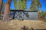 Nestled amongst tall pine trees, this dark gray home offers a secluded mountain retreat.