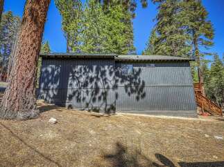 Nestled amongst tall pine trees, this dark gray home offers a secluded mountain retreat.