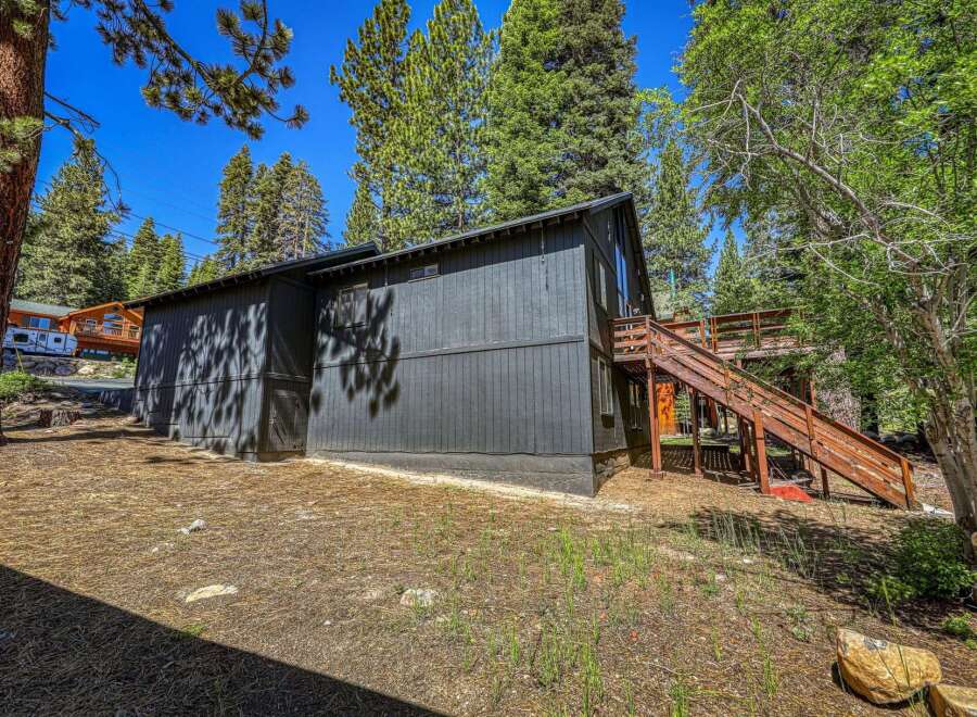 Nestled amongst tall pine trees, this dark-paneled home offers a unique mountain retreat.