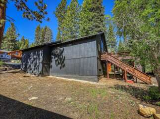 Nestled amongst tall pine trees, this dark-paneled home offers a unique mountain retreat.