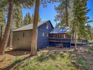 Nestled amidst towering pine trees, this charming dark blue home offers a serene mountain retreat.