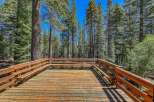 Enjoy the serene mountain lifestyle from this expansive wooden deck, perfect for outdoor gatherings or quiet relaxation amidst towering pine trees.